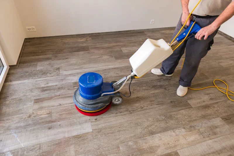 bodenreinigung-903437c6 Professionelle Bodenreinigung mit einer Einscheibenmaschine auf einem grauen Holzboden.