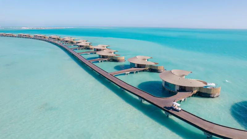 Luxuriöse Overwater-Villen im Roten Meer in Saudi-Arabien, verbunden durch einen langen Steg über türkisblauem Wasser.