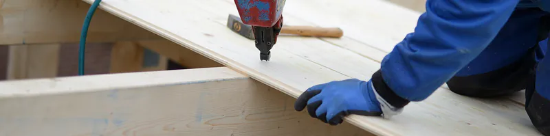 rauspund-cbbc9bdd Handwerker befestigt mit einem Druckluftnagler Rauspund-Bretter auf einer Holzunterkonstruktion.