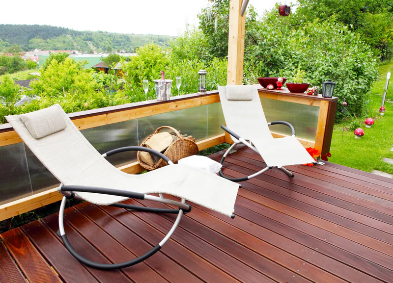 bangkirai-terrasse-holz-disselnmeyer-b1330a68 Zwei moderne Liegestühle auf einer hochwertigen Bangkirai-Holzterrasse mit Blick ins Grüne im Garten.