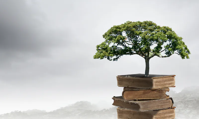 Ein kleiner Baum wächst aus einem Stapel alter Bücher als Symbol für Wissen und das Naturmaterial Holz.