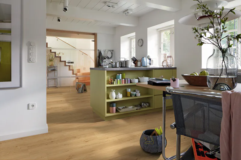 Heller Allround DD700S Designboden in einer offenen Wohnküche mit hellen Holzoptik-Dielen und moderner Kücheninsel.