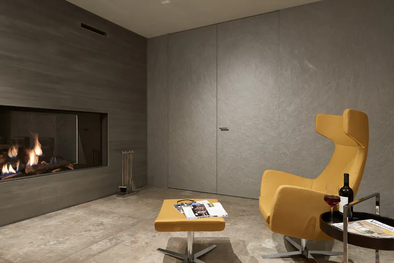 Moderne, flächenbündige Grauthoff Innentür in einem Wohnraum mit Kamin und gelbem Sessel.