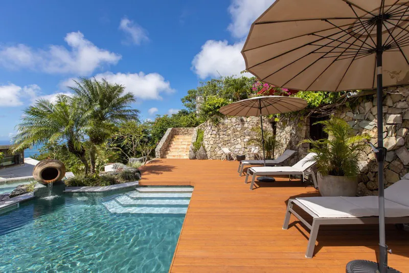 moso-terrasse-7133b9fa Luxuriöse Moso-Terrasse mit Pool, modernen Sonnenliegen und Sonnenschirmen in einem tropischen Garten unter blauem Himmel.