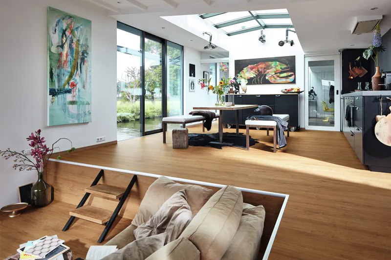 Moderner Wohnraum mit MeisterDesign DD Ambiente Bodenbelag, offener Wohnküche auf zwei Ebenen und großzügigem Lichteinfall durch Dachfenster.
