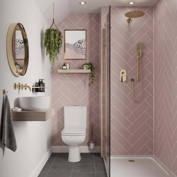 Modernes Badezimmer mit hellrosa Wandpaneelen in Fischgrätoptik von Disselnmeyer, ergänzt durch goldene Armaturen und eine Dusche.