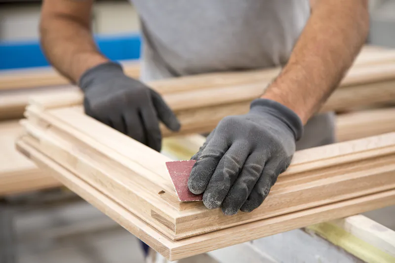fensterkantel-86ede5b2 Handwerker schleift eine Fensterkantel aus Holz mit einem Schleifklotz in der Werkstatt.